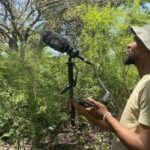 Personne enregistrant les sons de la forêt avec un microphone directionnel