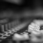 Gros plan en noir et blanc sur les commandes d’une console de mixage