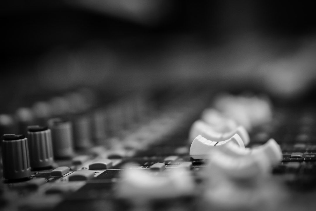 Gros plan en noir et blanc sur les commandes d’une console de mixage